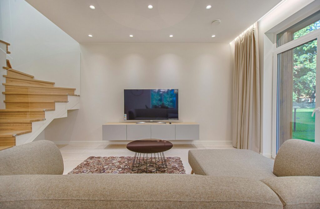 pexels-photo-1571458-1571458 Contemporary living room with stylish sofa, TV, and staircase, offering a cozy interior design setting.